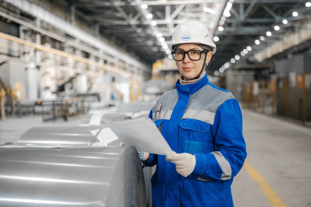 Factory employee reviewing production documents beside industrial rolls
